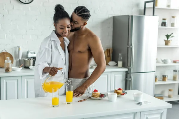 African American Pacar Mencium Pacar Sementara Dia Menuangkan Jus Jeruk — Stok Foto