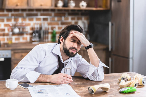 loner businessman having headache and hangover at kitchen