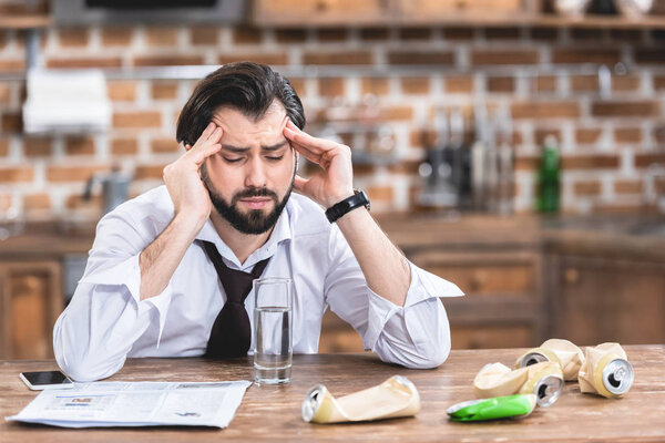 handsome loner businessman having headache and hangover at kitchen