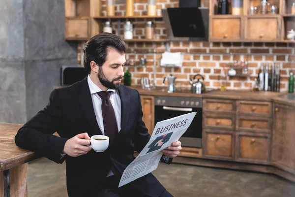 新聞を読むと キッチンで朝の一杯のコーヒーを保持しているハンサムな一匹狼実業家 — ストック写真