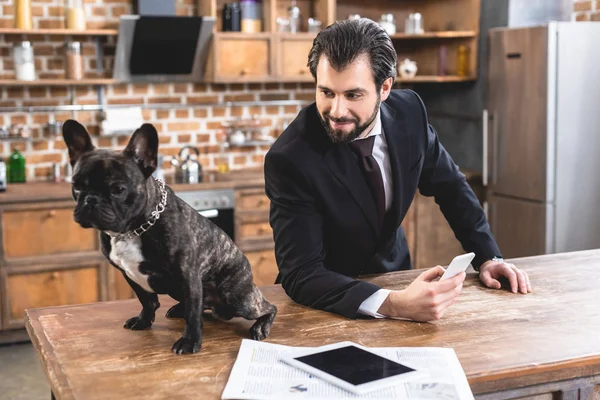 Hombre Negocios Solitario Mirando Bulldog Mesa Sosteniendo Teléfono Inteligente Cocina — Foto de Stock