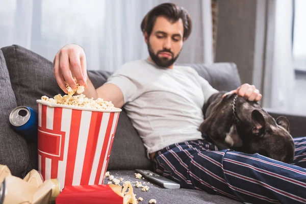 Schöner Einzelgänger Sitzt Mit Bulldogge Und Nimmt Popcorn Auf Sofa — Stockfoto