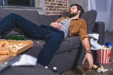  yalnız adam bardak viski kirli oturma odasında kanepede yatıyor