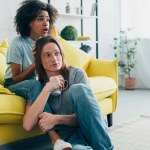 Asustada pareja multiétnica viendo la televisión en casa