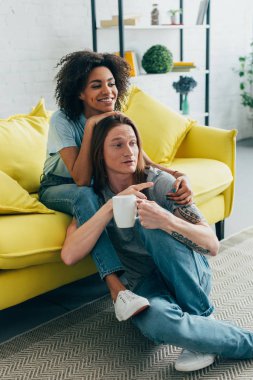 TV izlerken, erkek tv ekranında gösteren dövmeli ele kucaklayan çekici Afrikalı-Amerikalı kadın