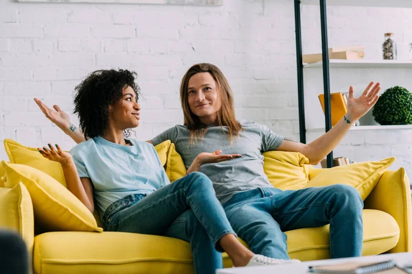 Pareja Sonriente Multiétnica Con Brazos Anchos Sentados Sofá Casa — Foto de Stock