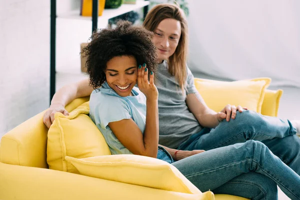 african american young woman shying and turning away face from boyfriend on sofa