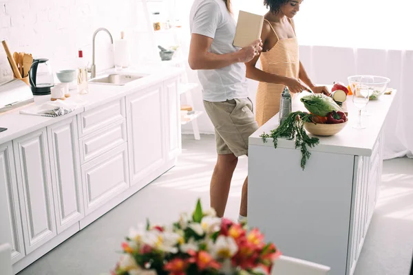 Imagem Cortada Homem Com Livro Receitas Namorada Cortando Legumes Cozinha — Fotografia de Stock