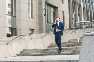 işadamı kahve ile telefonla merdiven işletme binası yakınındaki tarafından yürürken konuşmaya başladın