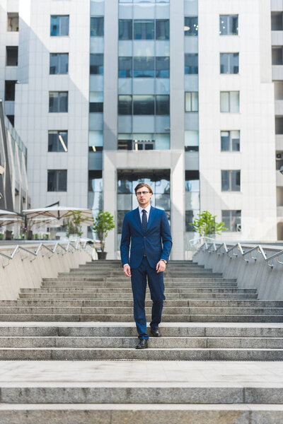 stylish young businessman walking down stairs in business district