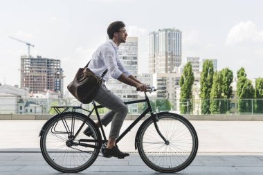 vintage Bisiklet şehir sokak sürme şık giysiler içinde genç adam yan görünüm