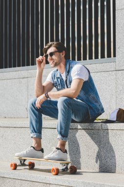 kaykay uzağa arıyorsunuz ile merdivenlerde oturan yakışıklı genç kaykaycı