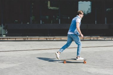 Genç kaykaycı longboard street tarafından sürme yan görünüm