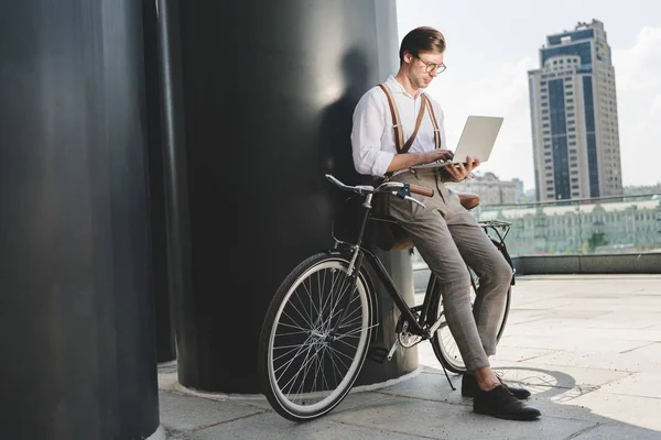 Стильный Молодой Человек Работает Ноутбуком Опираясь Винтажный Велосипед — стоковое фото