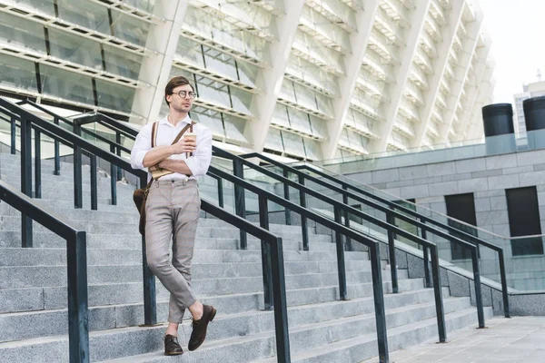 魅力的な若い男の本とコーヒー スタジアムの前の階段の上に立って行く — ストック写真
