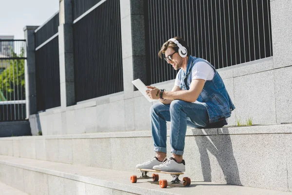 Stylish Young Man Skateboard Listening Music Headphones Tablet Street — Stock Photo, Image