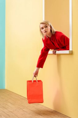 young fashionable woman in red clothing with red shopping bags looking out decorative window clipart