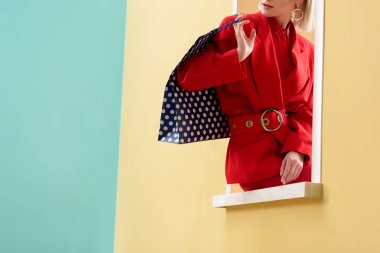 nokta desenli dekoratif penceresinde oturan alışveriş çantası ile şık kadın görüntüsünü kırpılmış