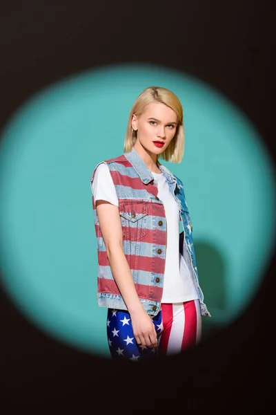 青い背景にポーズ アメリカ旗パターンのデニム ジャケットでスタイリッシュな若い女性の肖像画  — 無料ストックフォト