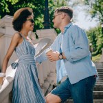 Side view of stylish multicultural couple with coffee cups standing on stairs