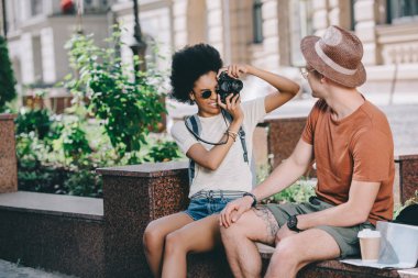 young female traveler taking picture of boyfriend on camera 