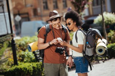 young couple of tourists with smartphone looking for destination  clipart
