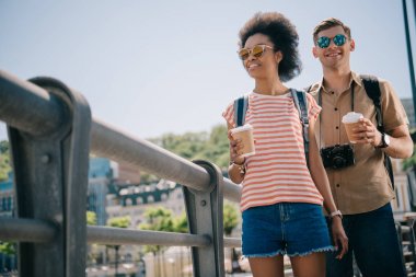 kağıt bardak kahve ve kamera ile turistlerin çok ırklı çiftin düşük açılı görünüş