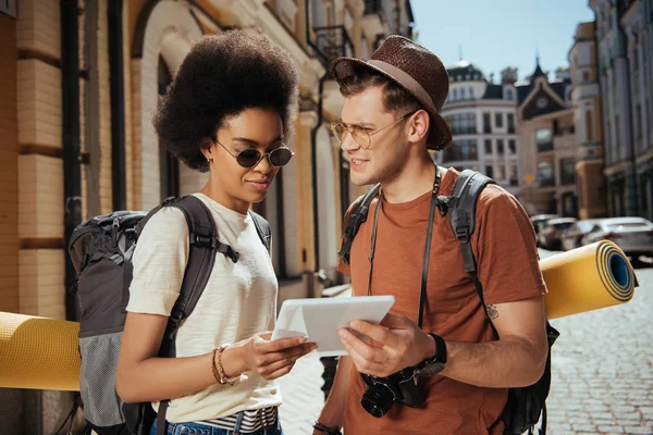 young multiethnic couple of tourists with camera and digital tablet