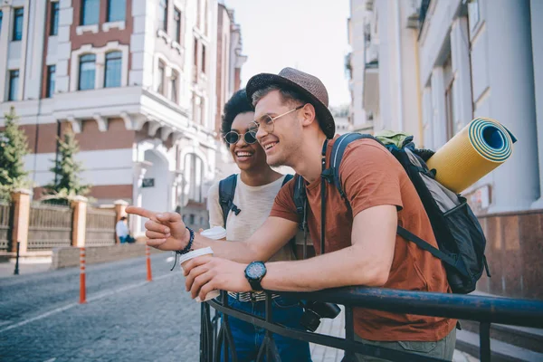 Joven Sonriente Turista Masculino Con Taza Café Señalando Con Dedo — Foto de Stock