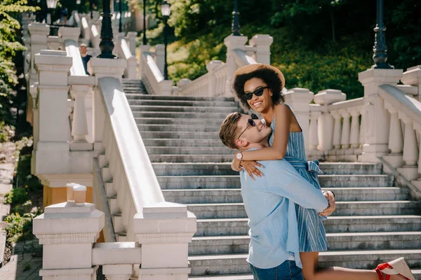 Happy Young Man Holding African American Girlfriend Stairs Park — Free Stock Photo