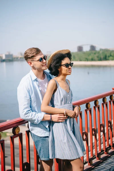 Multikulturelles Paar Mit Sonnenbrille Steht Auf Brücke Über Fluss — Stockfoto
