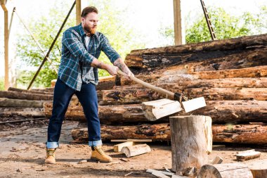 lumberjack in checkered shirt chopping log at sawmill  clipart