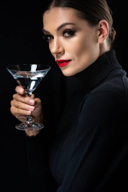 Güzel, zarif bir kadın, kırmızı dudaklı, siyah bardakta martini bardağı tutan.