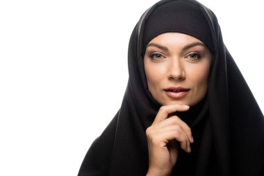 Beyaz tenli, tesettürlü, güzel, genç Müslüman kadın çenesine dokunuyor.