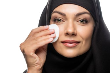 tesettürlü, tesettürlü, gülümseyen, genç Müslüman bir kadın pamuklu bezle yüzünü siliyor.