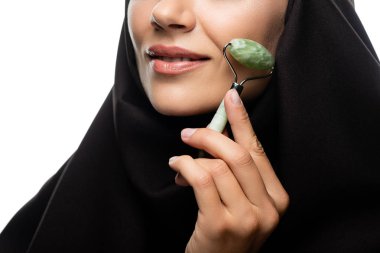 Türbanlı genç Müslüman kadının beyaza izole edilmiş yeşil silindir kullandığı kısmen görülüyor.