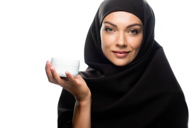 tesettürlü genç müslüman kadın kozmetik kremi ile beyaz tencereyi tutuyor.