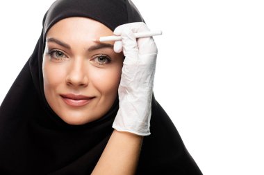 Estetik cerrah, genç Müslüman kadını beyaza izole edilmiş estetik ameliyata götürüyor.