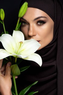 Güzel Müslüman kadın dumanlı gözleriyle kara zambak tutuyor.