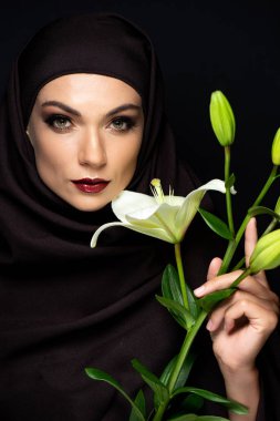 Kırmızı dudaklı, tesettürlü çekici Müslüman kadın siyah zambak tutuyor.