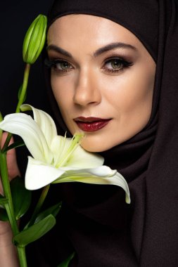 Kırmızı dudaklı, tesettürlü çekici Müslüman kadın siyah zambak tutuyor.