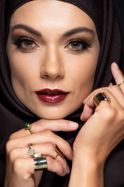 Altın yüzüklerle süslenmiş tesettürlü güzel Müslüman kadın siyahlara izole edilmiş.