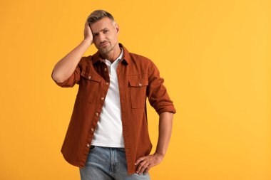 Kafaya dokunan ve elleri kalçasında duran mutsuz adam portakalda soyutlanmış. 