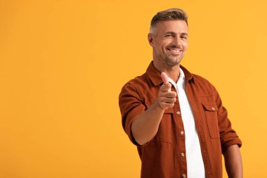 Seçici odak noktası, turuncu üzerine parmak işareti yapan neşeli adam. 
