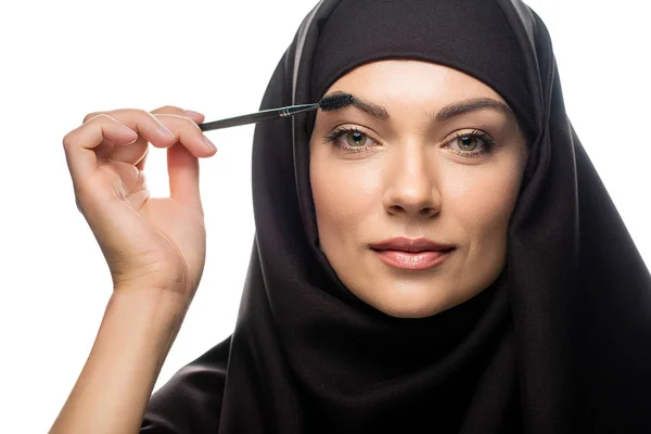 头戴头巾的年轻穆斯林妇女将睫毛膏涂在白色孤立的睫毛上 — 图库照片