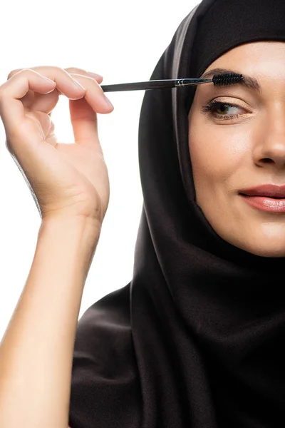 ヒジャーブの若いイスラム教徒女性の部分的な見解白で隔離されたまつ毛にマスカラを適用します — ストック写真