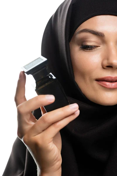 ヒジャーブの若いイスラム教徒の女性の部分的な見解白に隔離された香水のボトルを保持 — ストック写真