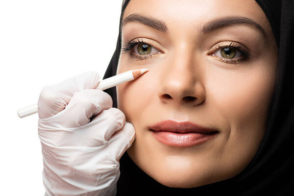plastic surgeon marking young Muslim woman face for plastic surgery isolated on white
