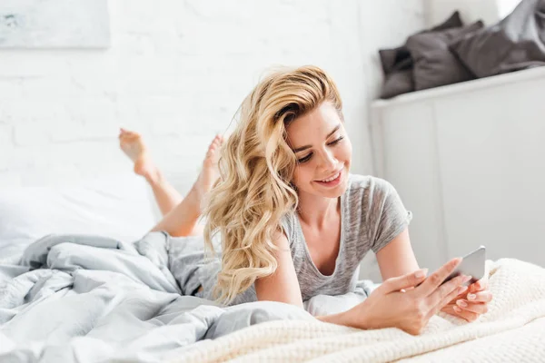 Selective Focus Cheerful Girl Using Smartphone While Lying Bed — Stock Photo, Image