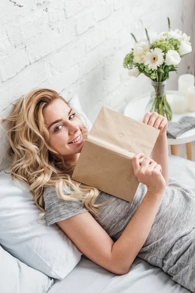 Щаслива Жінка Тримає Книгу Лежачи Ліжку — стокове фото